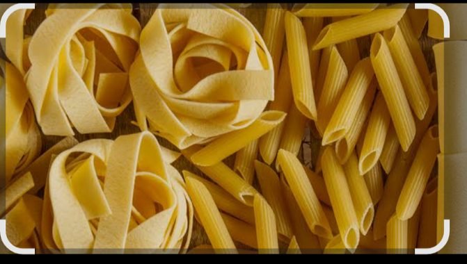 Top-down view of dry Italian pasta with tagliatelle nests and penne rigate on rustic wood